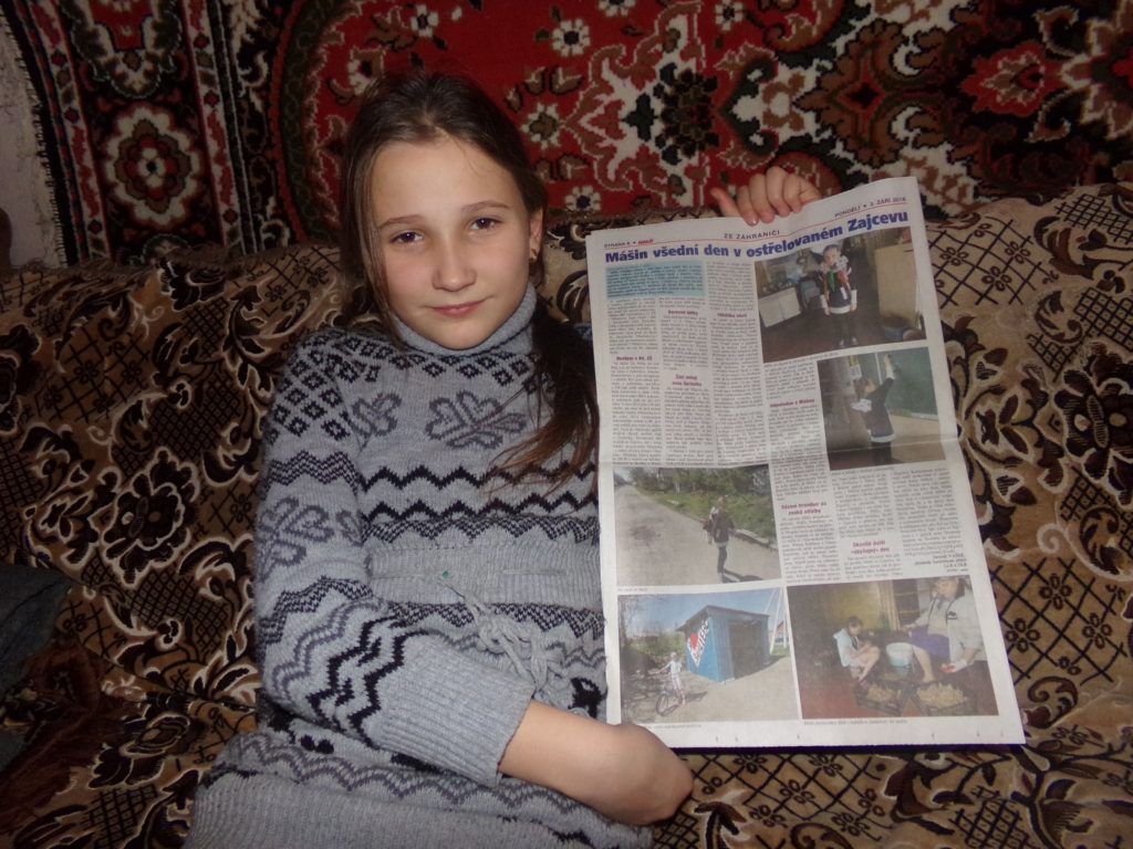 Máša Ryžkova, 10, po předání dárků, Zajcevo, DLR, prosinec 2019 Máša ukazuje článek o sobě v Haló novinách-reportáž z jara 2019